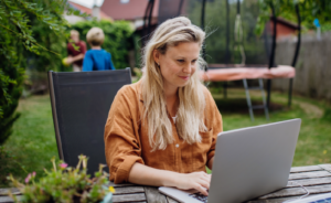 Woman doing online professional development on a laptop sitting at a park