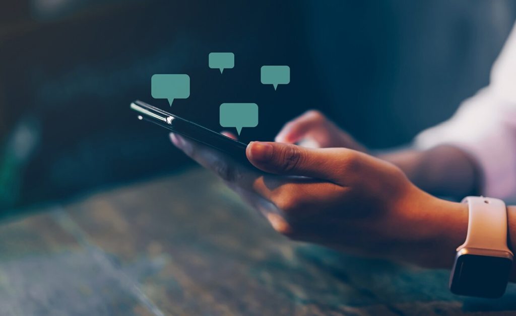 Person using a smartphone with chat bubbles.