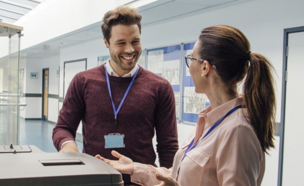 Two teachers talking in a hallway at the copier.