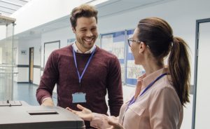 Two teachers talking in a hallway at the copier.