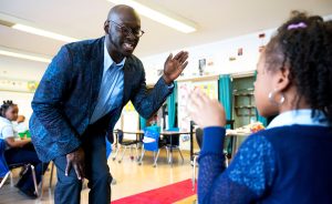Shantram Hawkins, Ace Alum, giving a young female student a high-five in his classroom.