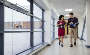 Two teachers walking and talking in a school hallway.