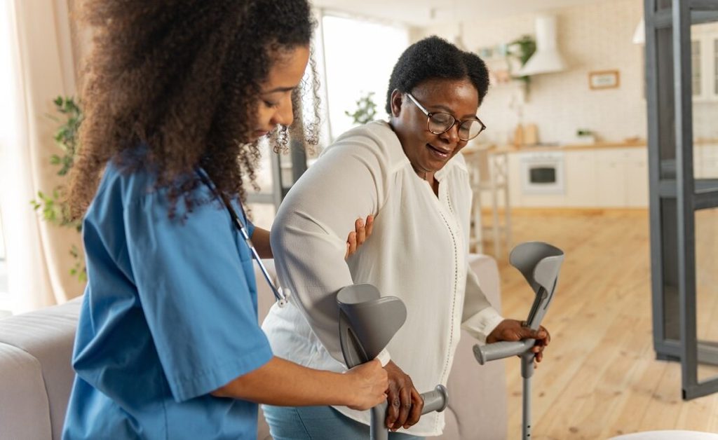 A nurse assisting a patient at home with crutches.
