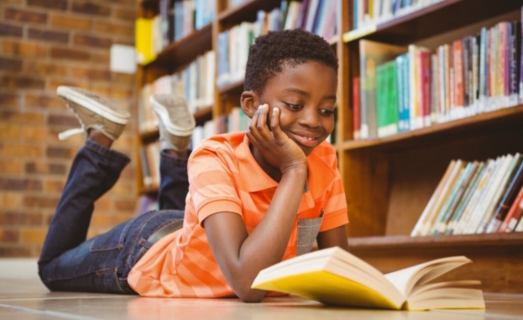 Child reading a book in a library.
