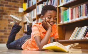 Child reading a book in a library.