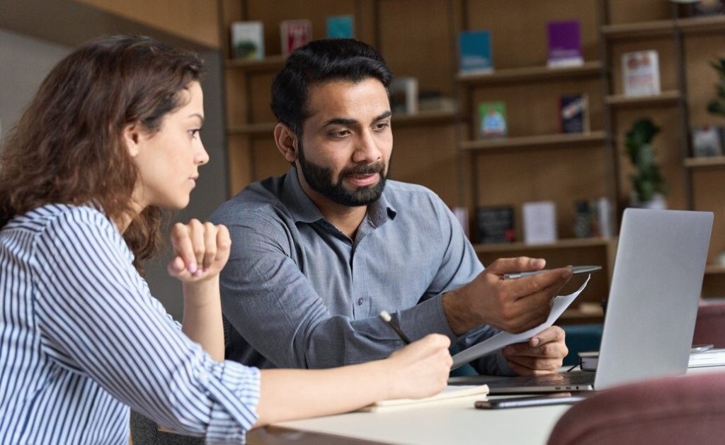 Two teachers working together at a table with a laptop.