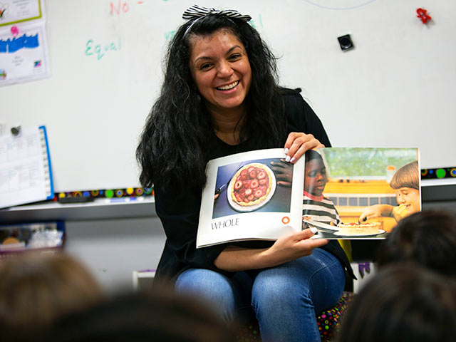 Female teacher reading a book to a group of students