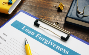 Clipboard holding a form titled "Loan Forgiveness," across which is laying a yellow pen