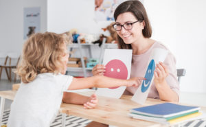 Teacher holding up emotion cue cards for a student to point to