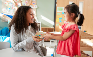 Female teacher receiving a gift from a young student for teacher appreciation week