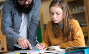 Teacher helping student with assignment in classroom