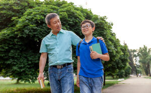 Parent walking with a child who is carrying backpack and homework