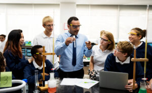 Science teacher engaging with interested students during science experiment